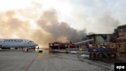 Дым над терминалом аэропорта в Карачи, на который было совершено вооруженное нападение, 9 июня 2014 года. 