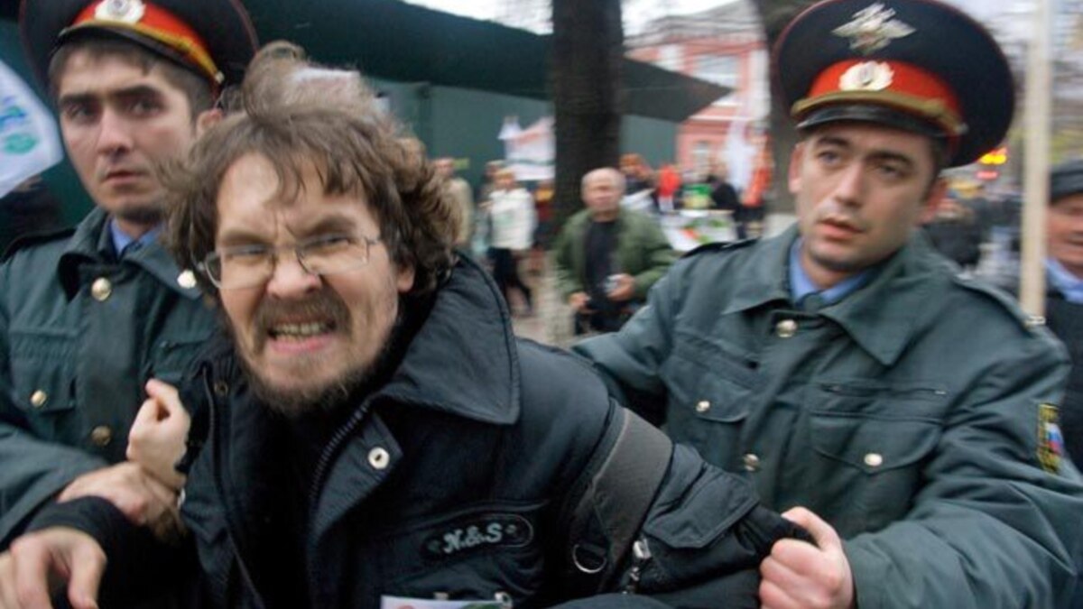 A police officer detains a climate activist after she sprayed