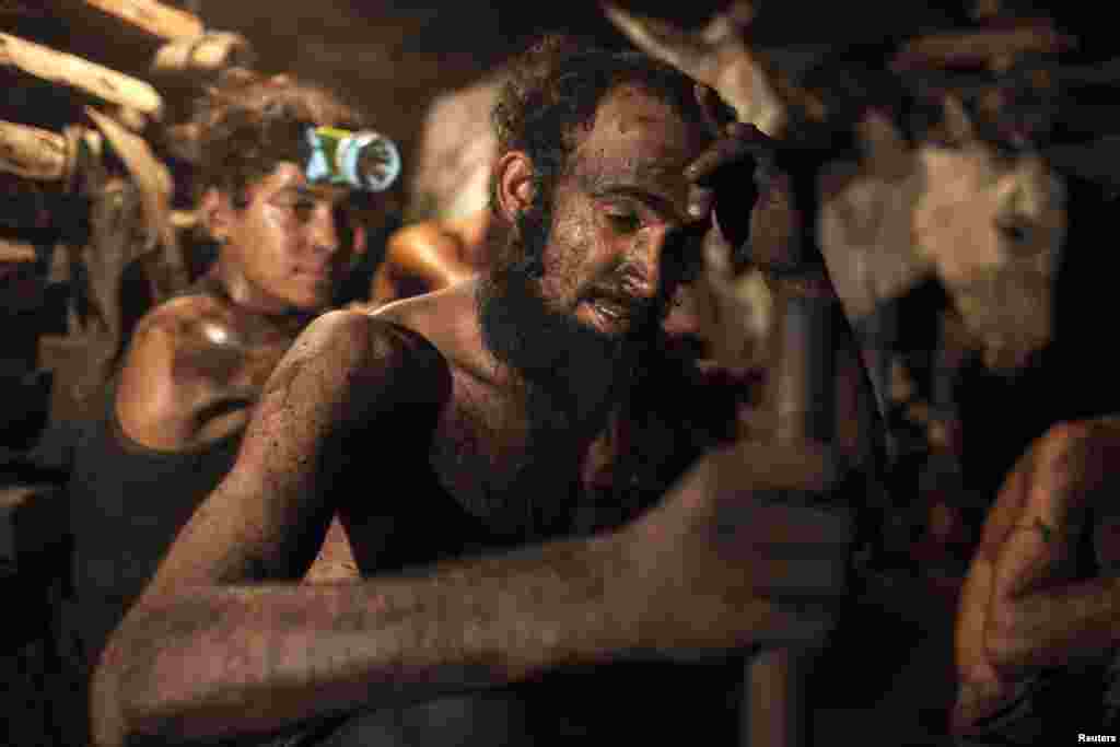 A miner wipes sweat from his forehead inside a coal mine.