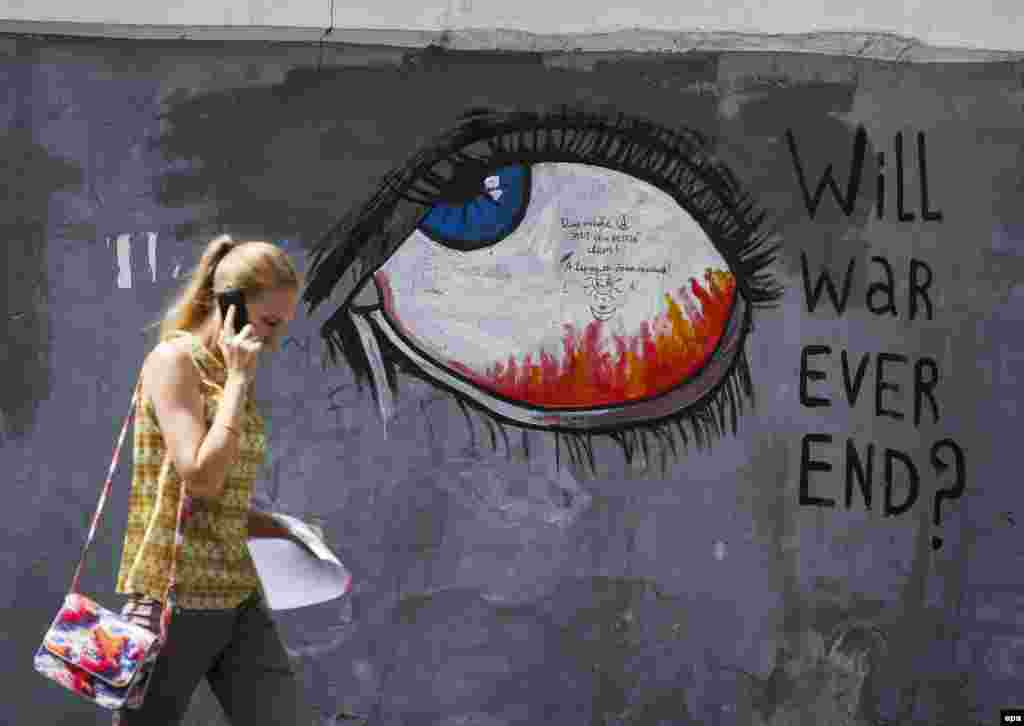 A woman walks next to graffiti in downtown Kyiv, Ukraine. More than 6,000 people have been killed in eastern Ukraine since pro-Russian rebels and the Ukrainian military began battling in April last year. (epa/Roman Pilipey)