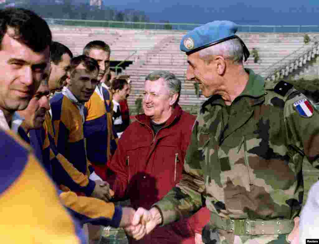 A French commander shakes hands with Bosnian rugby players before a friendly game betwen UN peacekeeping forces and a local team some years after the Balkan conflict.