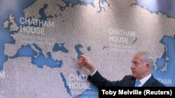 Israel's Prime Minister Benjamin Netanyahu gestures towards a world map as he attends a question and answer event on Israel's foreign policy at Chatham House in London, Britain, November 3, 2017.