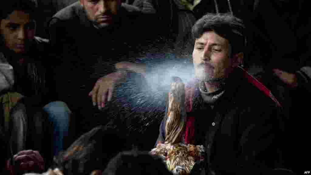 An Afghan man sprays his rooster&#39;s beak with water during a break between rounds of a weekly cockfight in Kabul on April 20. (AFP/Johannes Eisele) 