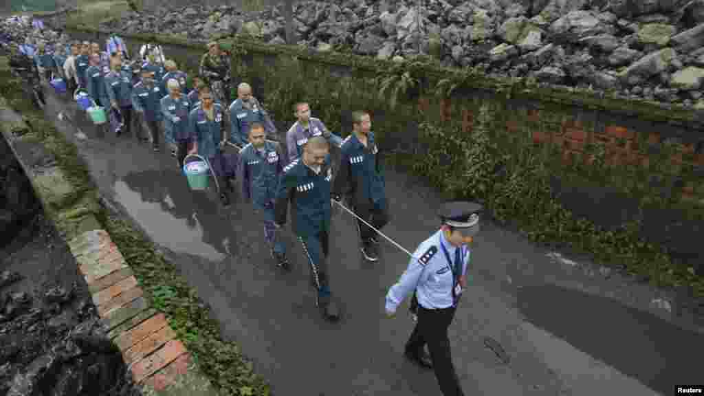 A Chinese policeman leads prisoners along a road in the Emei Mountain region, Sichuan Province,&nbsp; on September 27. The inmates were being moved to a new prison. (REUTERS)