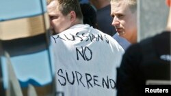 Russian soccer fans suspected of being involved in clashes, with one wearing a banner saying "Russia no surrender," are ushered off their bus after being stopped by gendarmes in Mandelieu near Cannes, France, on June 14.