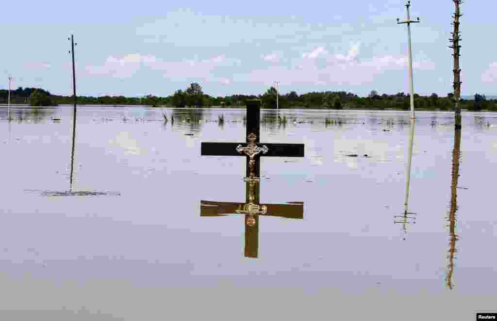 A cross is seen in floodwaters at a cemetery in the village of Vojskova, Bosnia-Herzegovina, on May 19. (Reuters/Srdjan Zivulovic)