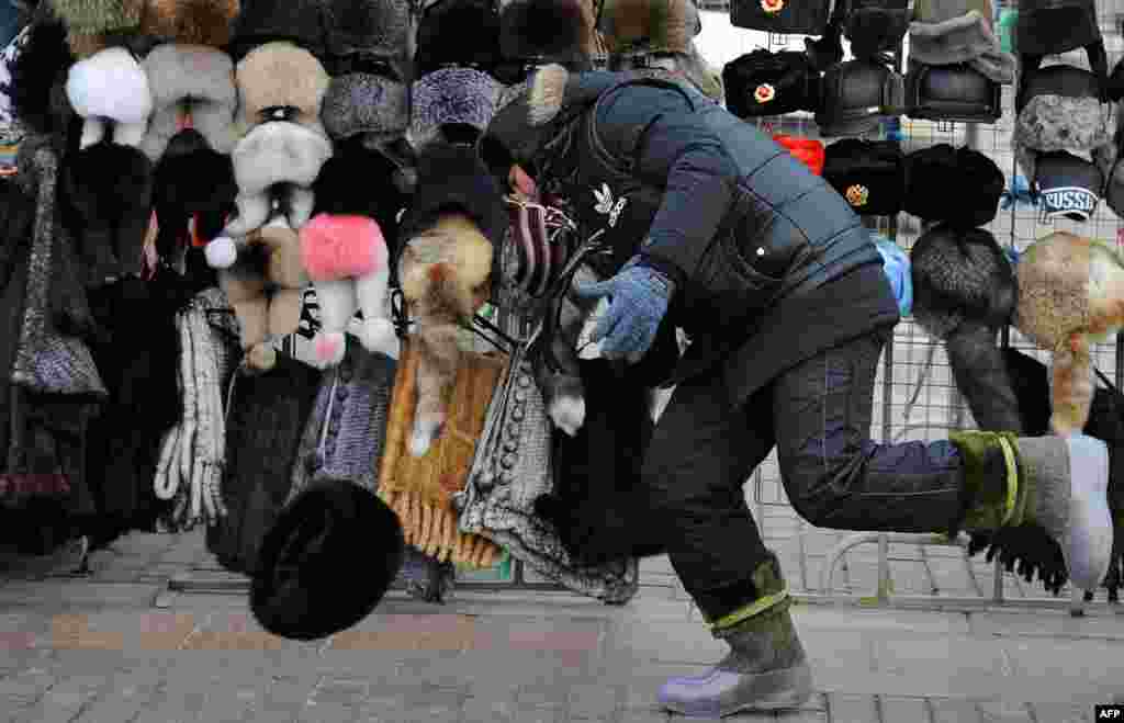 A street vendor tries to catch one of his winter hats, which was blown off a stand by strong winds on Red Square in Moscow.