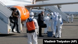 KAZAKHSTAN -- Kazakh medical workers check passengers for coronavirus symptoms as they arrive from Ukraine at an international airport in Almaty, March 27, 2020