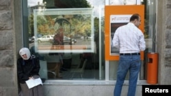 Georgia - A man uses an automated teller machine next to a woman begging for money on the street in the Georgian capital Tbilisi, 20Jun2012