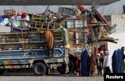An Afghan refugee family stands by trucks loaded with their belongings as they wait to go back to Afghanistan with others, at the United Nations High Commissioner for Refugees (UNHCR) office on the outskirts of Peshawar, Pakistan, in February 2015.
