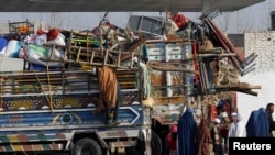 An Afghan refugee family stands by trucks loaded with their belongings as they wait to go back to Afghanistan on the outskirts of Peshawar.