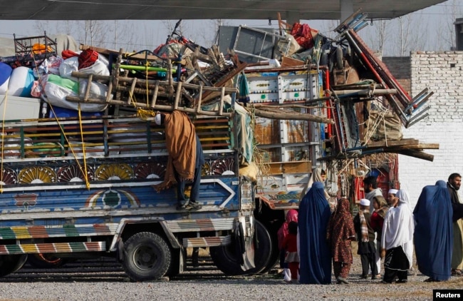 An Afghan refugee family stands by trucks loaded with their belongings as they wait to go back to Afghanistan with others, at the United Nations High Commissioner for Refugees (UNHCR) office on the outskirts of Peshawar, Pakistan, in February 2015.