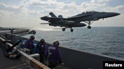 An F/A-18F fighter jet takes off from the U.S.S. John C. Stennis aircraft carrier during maneuvers in the Persian Gulf.