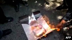 A YouTube video grab of antigovernment protesters burning a picture of Syrian President Bashar al-Assad during a demonstration in Irbin on June 15