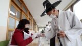 ROK -- South Korean Confucian scholar Yoo Bok-Yeob (R) wears plastic gloves amid concerns over the COVID-19 coronavirus ahead of casting his ballot for the parliamentary elections at a polling station in Nonsan on April 15, 2020. - Temperature checks on v
