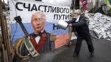 UKRAINE – A pro-European integration supporter washes a banner with an image of Russian President Vladimir Putin near a barricade in Independence Square where the supporters are holding a rally, in Kyiv January 9, 2014
