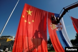 A worker adjusts Chinese and Serbian flags for the upcoming visit of Chinese President Xi Jinping on the site of what used to be China's embassy in Belgrade in June 2016.