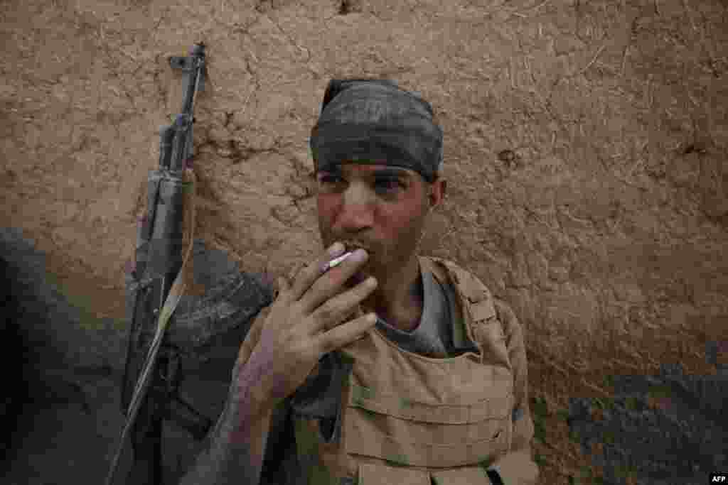 A member of the Iraqi government forces smokes a cigarette as they rest in the village of Al-Khuwayn, south of Mosul, after recapturing it from Islamic State (IS) militants on October 23. (AFP/Ahmad al-Rubaye)