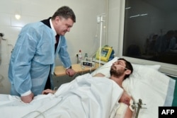 Ukrainian President Petro Poroshenko talks to a serviceman wounded during operations against pro-Russia militants in the east of the country during his visit to a military hospital in the northeastern city of Kharkiv on February 3.