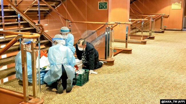 Медики у масках та захисному одязі на одній з палуб круїзного корабля Diamond Princess біля порту Йокогама. За офіціними даними, на борту – 3711 людей (команда і пасажири)