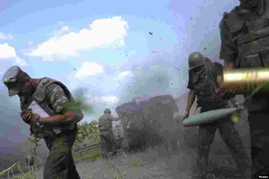 Ukrainian servicemen take cover after firing their artillery during a military operation against pro-Russia separatists near Pervomaysk in the eastern Luhansk region on August 2, 2014.