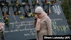 A woman pays respects at a memorial for people killed in clashes with security forces six years ago in Kyiv. 