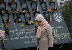 A woman pays respects at a memorial for people killed in clashes with security forces six years ago in Kyiv.
