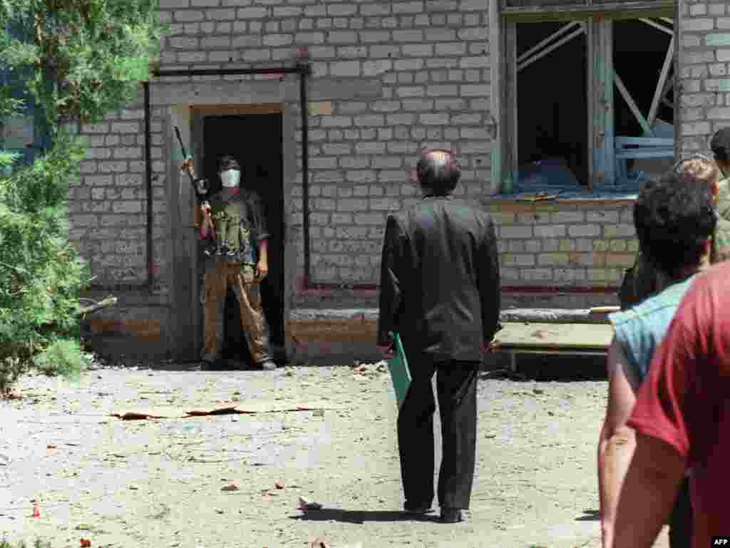 An unidentified Russian deputy talks with a Chechen fighter at the entrance of the Budennovsk hospital. The Chechen hostage-takers demand an end to the war, and direct talks. Russian President Boris Yeltsin calls the events&nbsp;&quot;unprecedented in cynicism and cruelty.&quot;