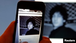 A photograph of Boston Marathon bombing suspect Dzhokhar Tsarnaev on his profile page for the Russian social-networking site Vkontakte (VK), as pictured on a monitor and a mobile phone in St. Petersburg, April 19, 2013.