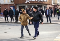 Полицейский ведет мужчину к автозаку во время митинга. Алматы, 22 февраля 2020 года.