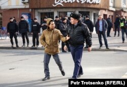 Полицейский ведёт мужчину к автозаку во время митинга. Алматы, 22 февраля 2020 года.