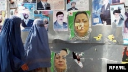 Two Afghan women in Kabul walk past posters of presidential and provincial candidates ahead of elections in 2009.