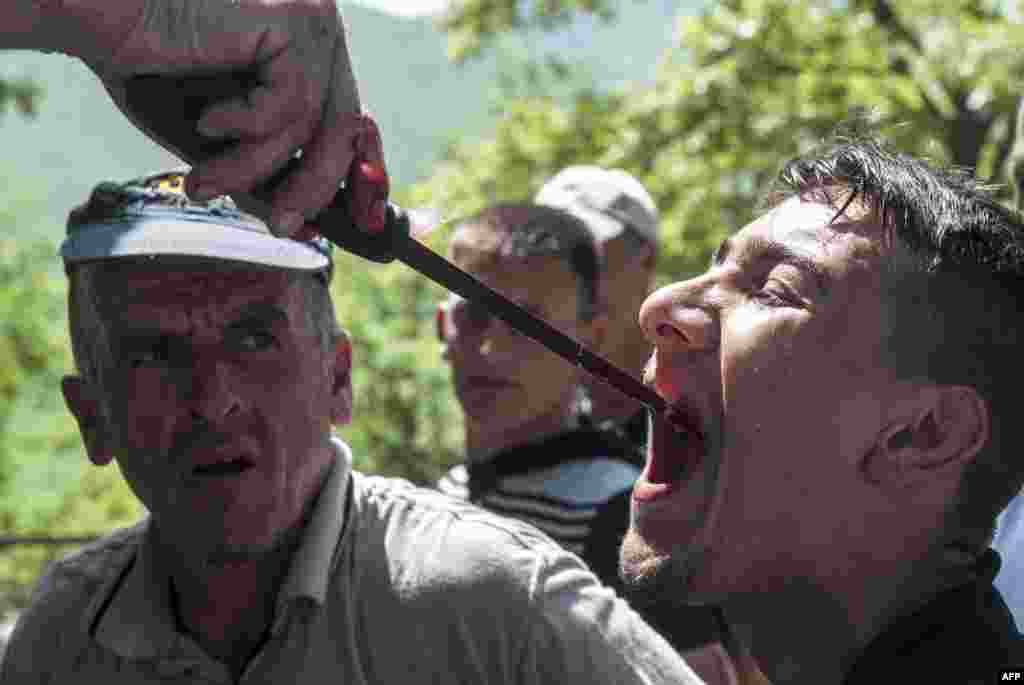 A Kosovo man drinks sheep blood with a butcher's knife as part of a tradition to prevent bad luck after sheep were slaughtered in the village of Babaj Bokes on May 6. (AFP/Armend Nimani)