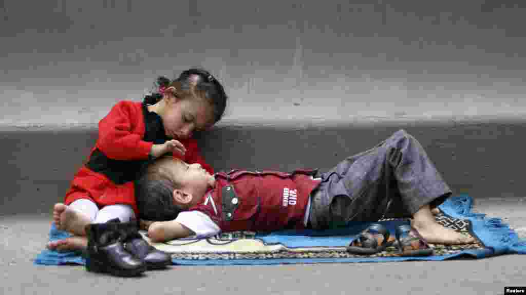 A girl leans over a boy as the weekly Friday Prayers are held during a rally in Sanaa on April 20. (Reuters/Mohamed al-Sayaghi)