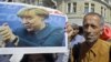 -- A migrant girl holds a poster of German Chancellor Angela Merkel as migrants walk in Budapest downtown after leaving the transit zone of the main train station, September 4, 2015