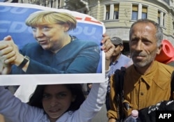 Мигрант держит в руках постер с фотографией Ангелы Меркель, Венгрия, 4 сентября 2015