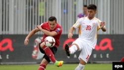 Pamje nga një ndeshje e kombëtares së Shqipërisë kundër Maqedonisë; futbollisti shqiptar Taulant Xhaka, me fanelë të kuqe, në duel me Gjorgjevin e Maqedonisë