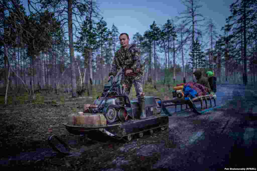 Dmitry Laziamov rides a snowmobile through the woods. 