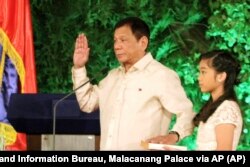 Новий президент Філіппін Родріго Дюртте складає присягу на Біблії, яку тримає його донька Вероніка. 2016 рік