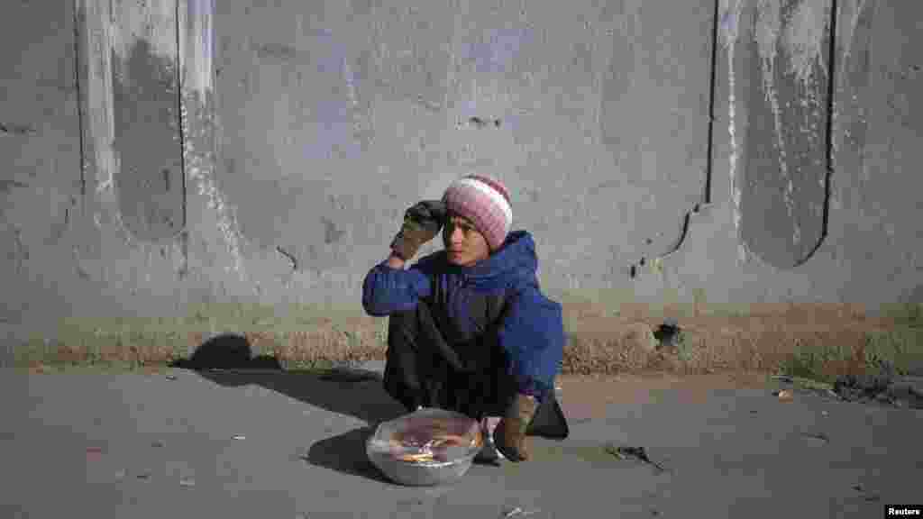 A boy selling homemade biscuits waits for customers on a sidewalk in Quetta, Pakistan, on December 30. (Reuters/Naseer Ahmed)