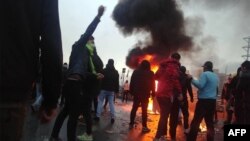 Iranian protesters gather around a fire during a demonstration against an increase in gasoline prices in the capital Tehran, on November 16, 2019. 