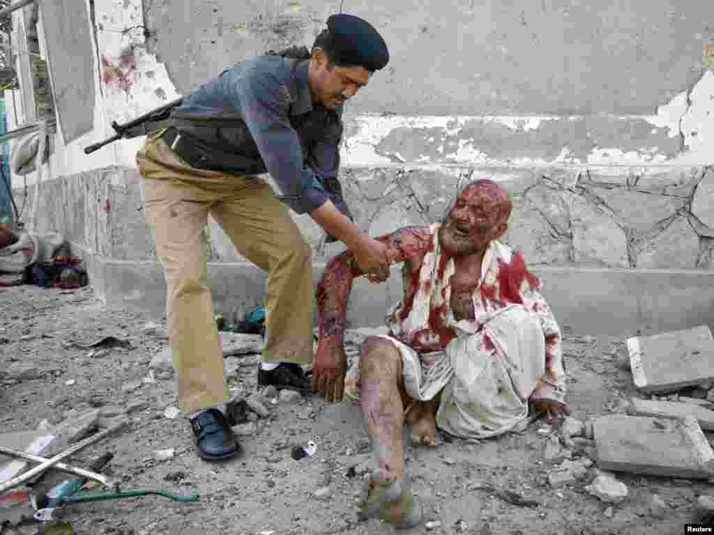 A Pakistani policeman assists an injured man at the site of a double suicide bombing in Quetta, on September 7. (Photo by Naseer Ahmed for Reuters)