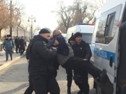 Полиция үкіметке қарсы шеруге келген адамды көлікке күштеп салып жатыр. Алматы, 22 ақпан 2020 жыл.