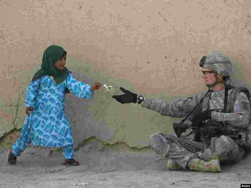 A U.S. Army soldier receives flowers from an Afghan girl during a patrol in the Arghandab valley in Kandahar Province. - Photo by Baz Ratner for Reuters