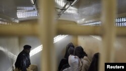 A Pakistani policeman sits beside detained and hooded men inside a secure police van in Bahawalpur, in Punjab province, in October.