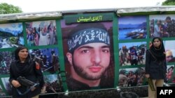 Pakistani policewomen stand guard beside a poster bearing the image of slain Indian Kashmir rebel Burhan Wani. (file photo)