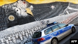 A German police car passes a mural painting featuring the emblematic U.S. eagle with a badge that reads "National Security Agency worldwide" at the Ehrenfeld railway embankment in Cologne on October 24, with revelations fresh of alleged U.S. eavesdropping on Chancellor Angela Merkel.