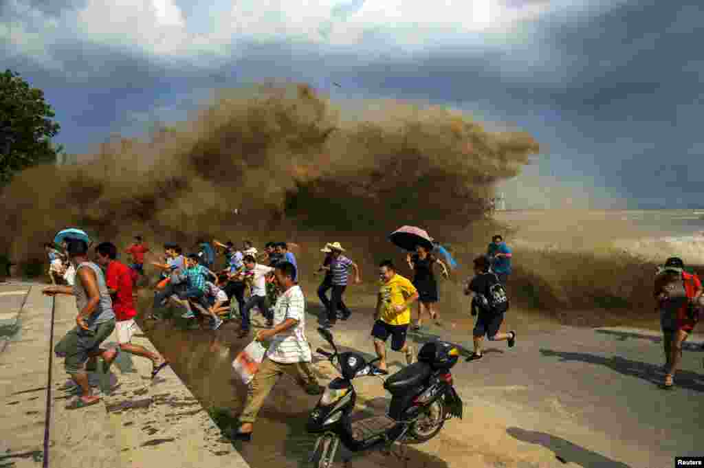 Visitors run away as waves from a tidal bore surge past a barrier on the banks of the Qiantang River in China&#39;s Hangzhou Zhejiang Province. (Reuters)