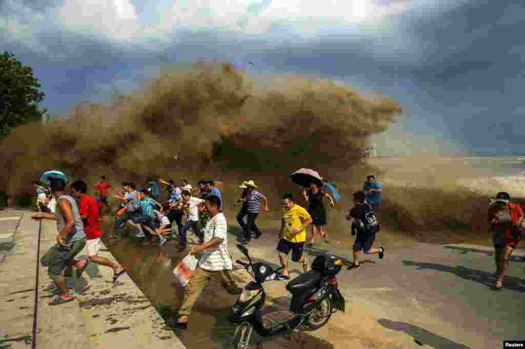 Visitors run away as waves from a tidal bore surge past a barrier on the banks of the Qiantang River in China's Hangzhou Zhejiang Province. (Reuters)