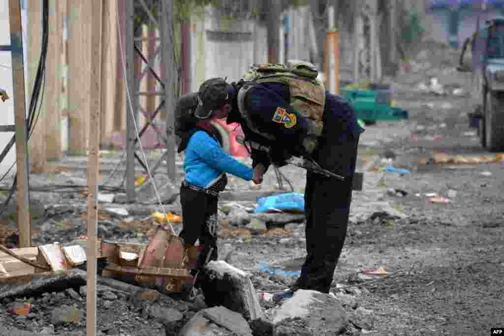 A member of the Iraqi special forces kisses a child in the neighborhood of Al-Barid, east of Mosul. (AFP/Mahmud al-Samarrai)